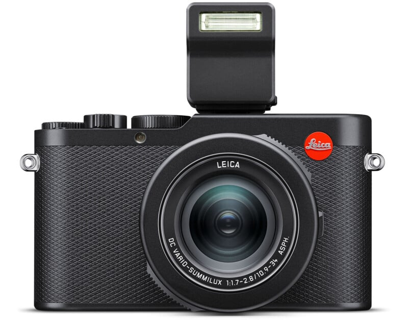 A black Leica digital camera with a textured handle and a large lens.  The flash is extended above the housing and the red Leica logo is prominently displayed at the top right.  The lens is labeled "DC VARIO-SUMMILUX 1:1.7-2.8/10.9-34 ASPH.