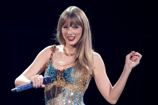 Taylor Swift on stage with microphone and glitter dress.