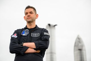 Jared Isaacman stands in front of spaceship prototypes