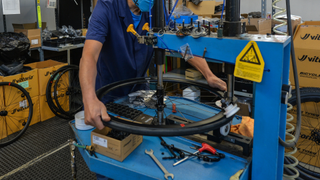 A factory worker assembles parts of a wheel