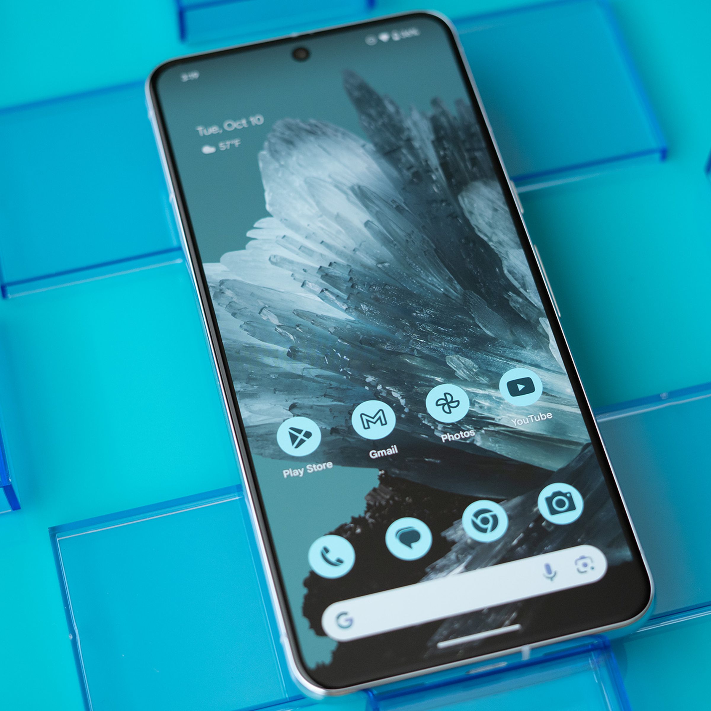 Google Pixel 8 Pro face up, showing the home screen and blue mineral background