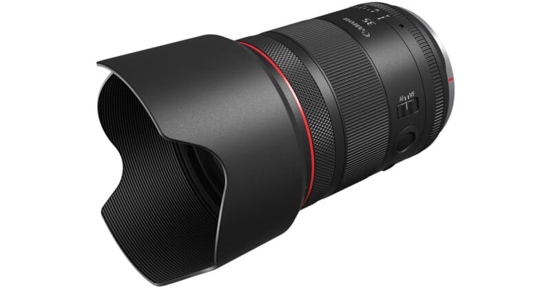 A Canon camera lens with a black body and a red ring on the front.  The lens has a ribbed focus ring, a button with a switch and a lens hood that protects the lens.  The Canon logo and specifications are visible on the body of the lens.