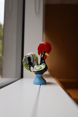 A statue of a rooster sitting on a windowsill