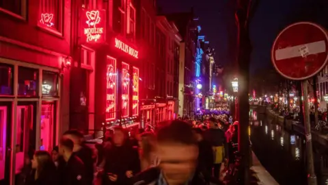 Getty Images Tourists along the Oudezijds Achterburgwal in the red light district of Amsterdam, Netherlands