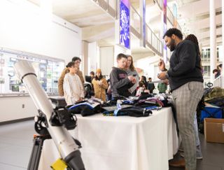 a man stands behind a table and hands out swag to children