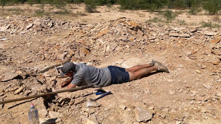 Photo of a man lying on his stomach digging in the ground