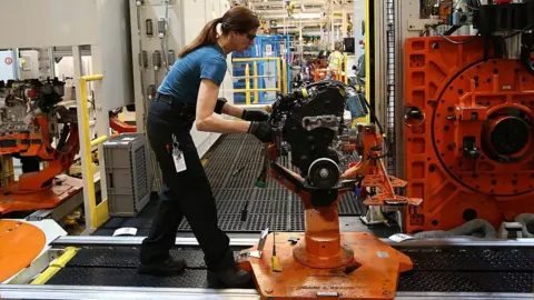 Getty Images Woman working on a black and orange machine in the factory