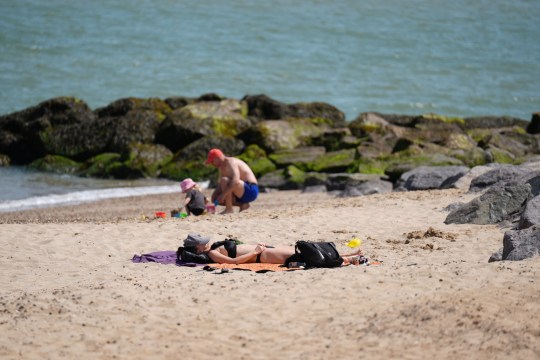 People sunbathe and build sand castles on a British beach