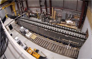 a long metal rail above a series of rectangular magnets in a hangar