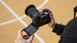 Nikon Z6 III camera in hand from over the photographer's shoulder with fold-out touchscreen