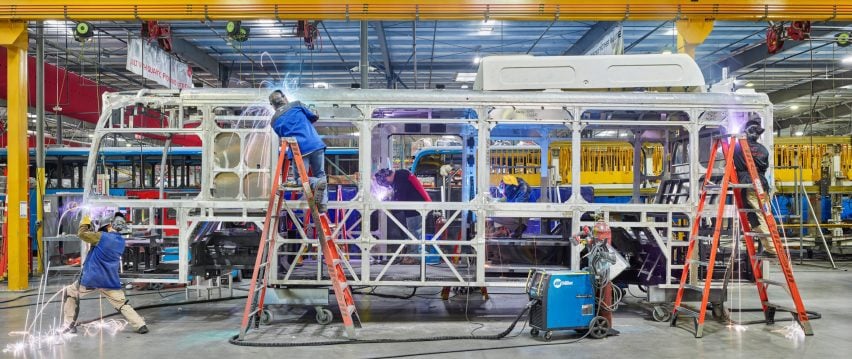 Workers weld parts to the steel frame of an electric public transport bus