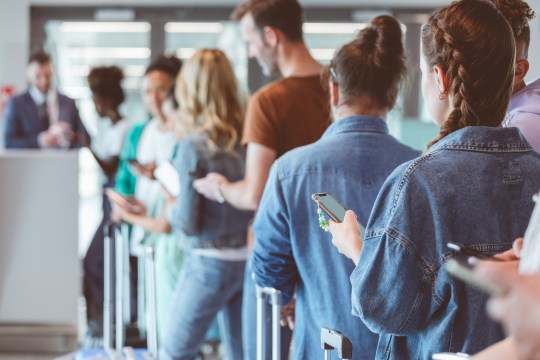 Passengers with luggage wait in line at the airport