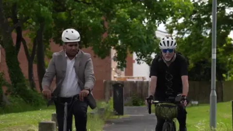 Faisal Islam and Gary Huett cycling on a path