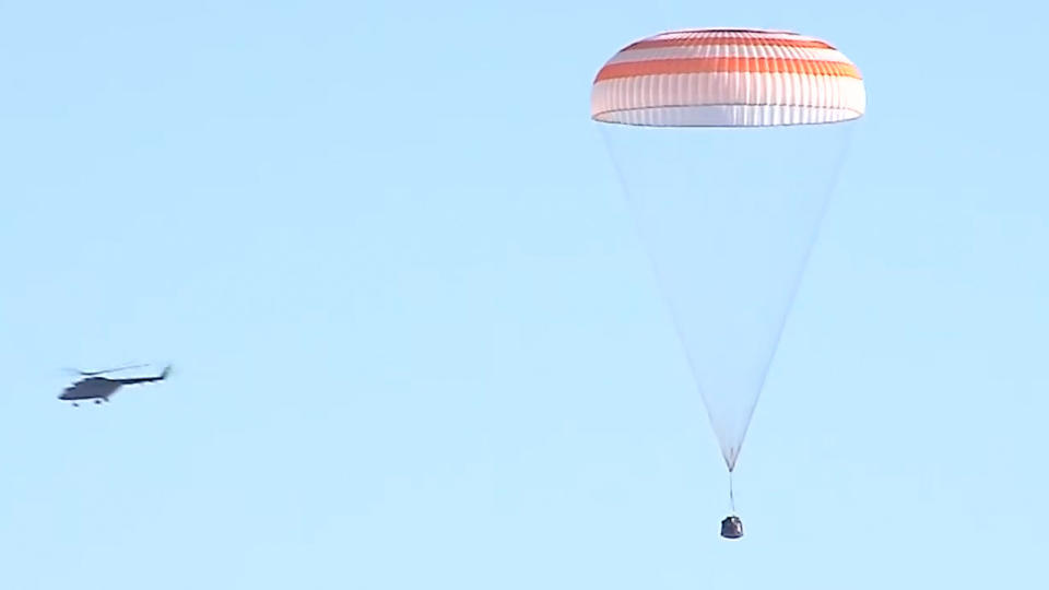 a spaceship under a parachute with a helicopter