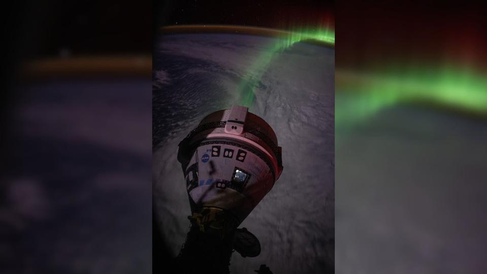 a cone-shaped spacecraft in front of a green aurora above the Earth, which is in the shadows