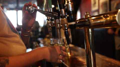 A bartender pours a pint