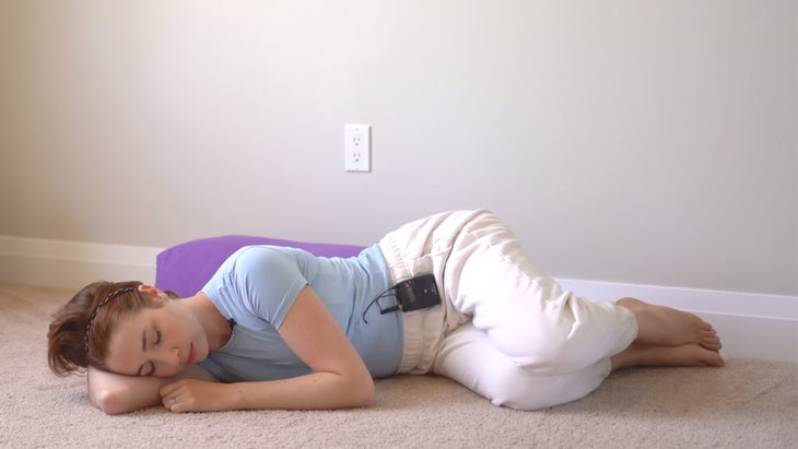 woman practicing yoga on her side by a wall