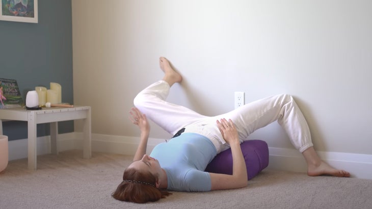 woman practicing yoga with her legs against a wall in different directions