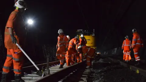 Network rail workers in reflective clothing repair the track in the Severn Tunnel