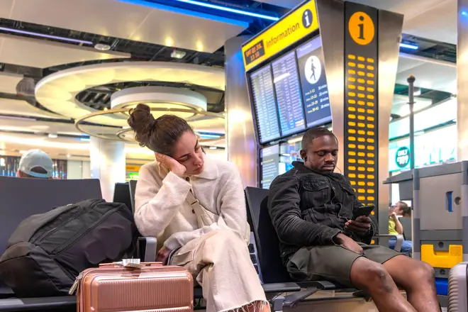 A man and a woman wait for their flight in the departure lounge at Heathrow Airport (archive photo).