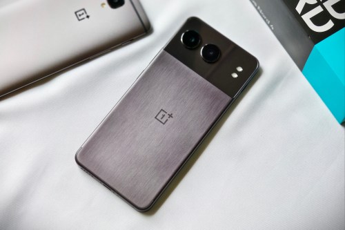 OnePlus Nord 4 in midnight black color with a metal unibody on a white fabric next to a bronze colored OnePlus 3T.