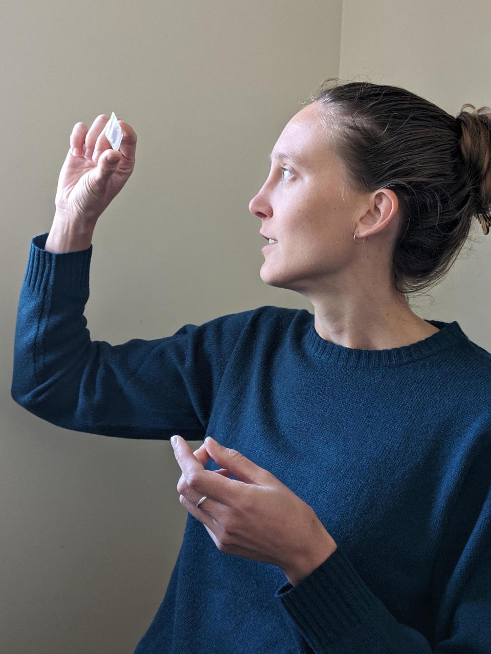 Doctor Erica Barlow in a dark blue sweater looks at the slide with her stone.