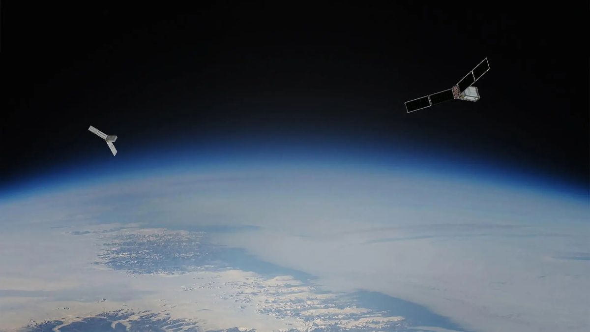 Two small rectangular satellites hover above earth on opposite sides. each has a dual-panel solar array extended from two sides. The curve of Earth below is hazy and blue.