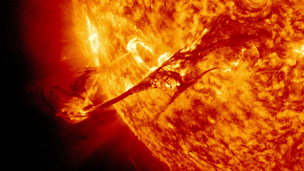 a raging fiery yellow and organge sun blazes from the right, filling two-thirds of the image. the star spits an arch of plasma high above its surface. so hot